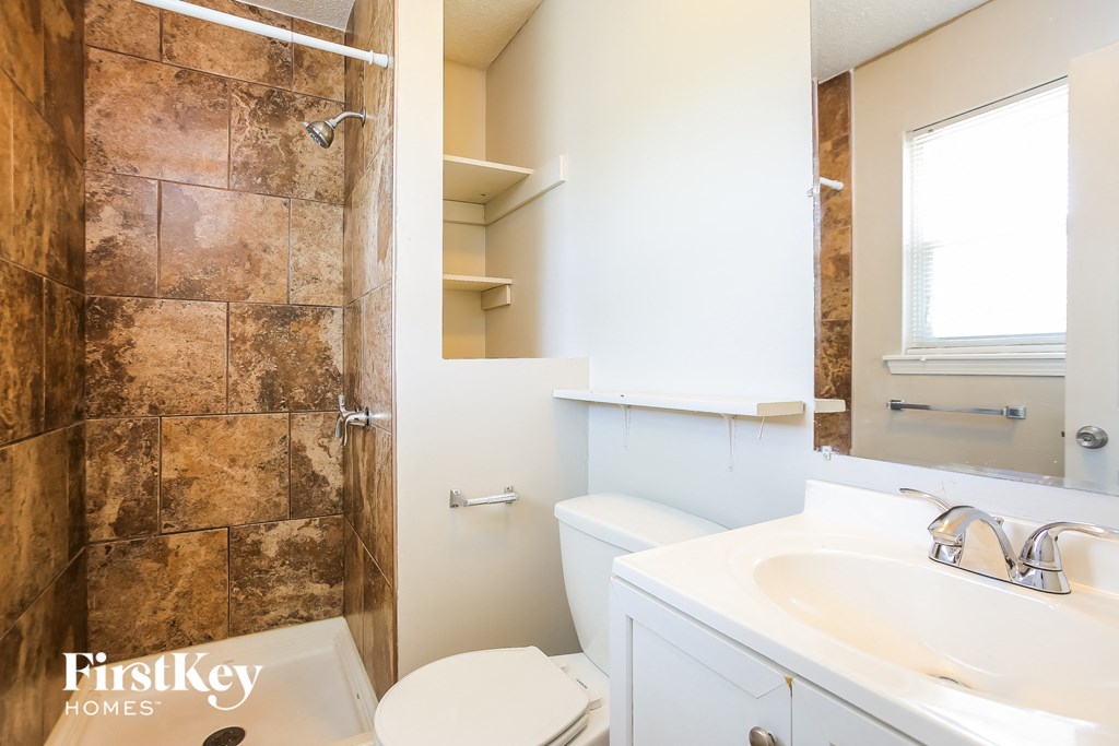 a bathroom with a toilet sink and shower and a mirror