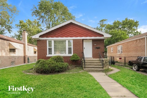 a small brick house with a sidewalk in front of it