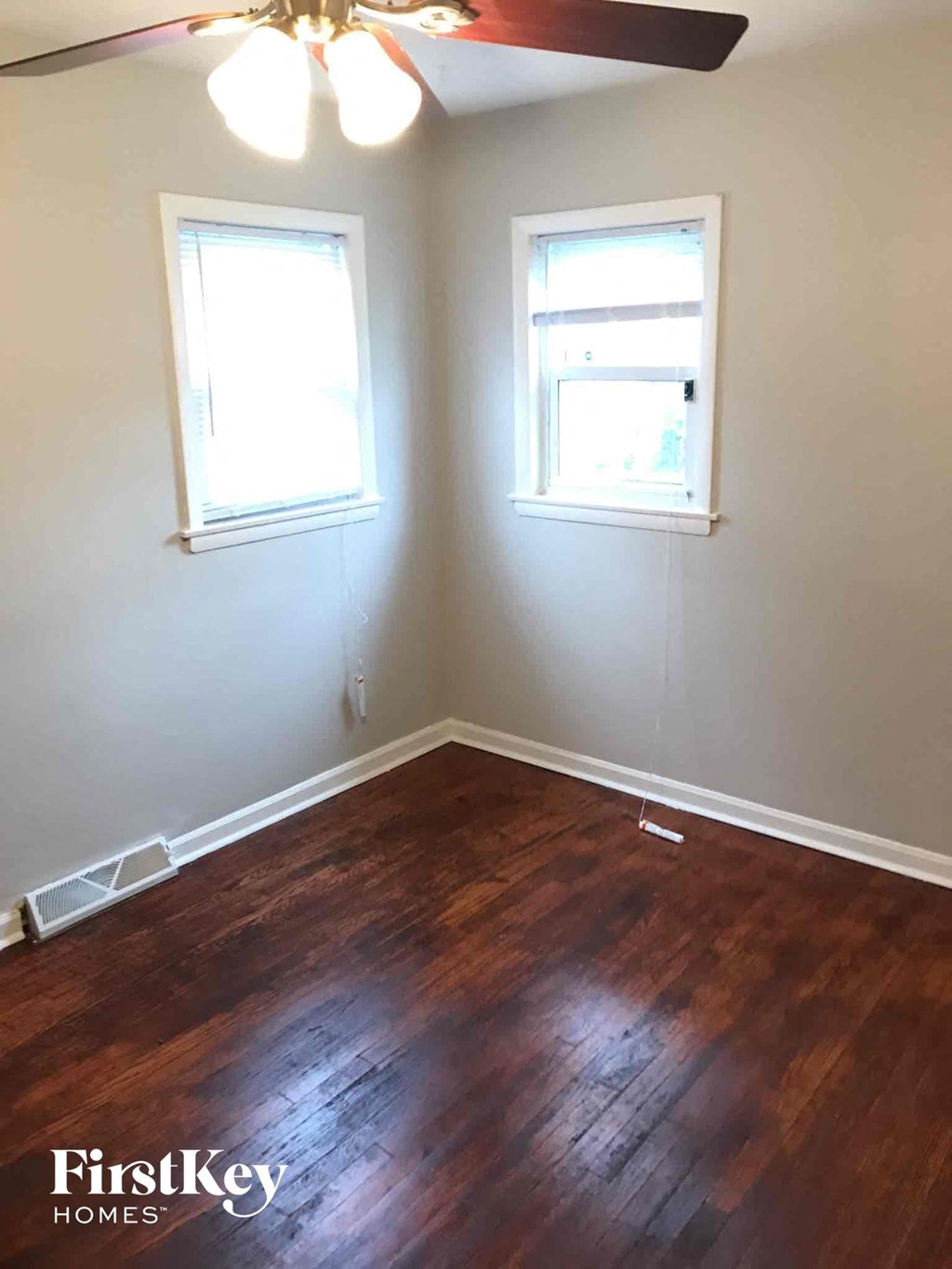 a room with a wooden floor and two windows