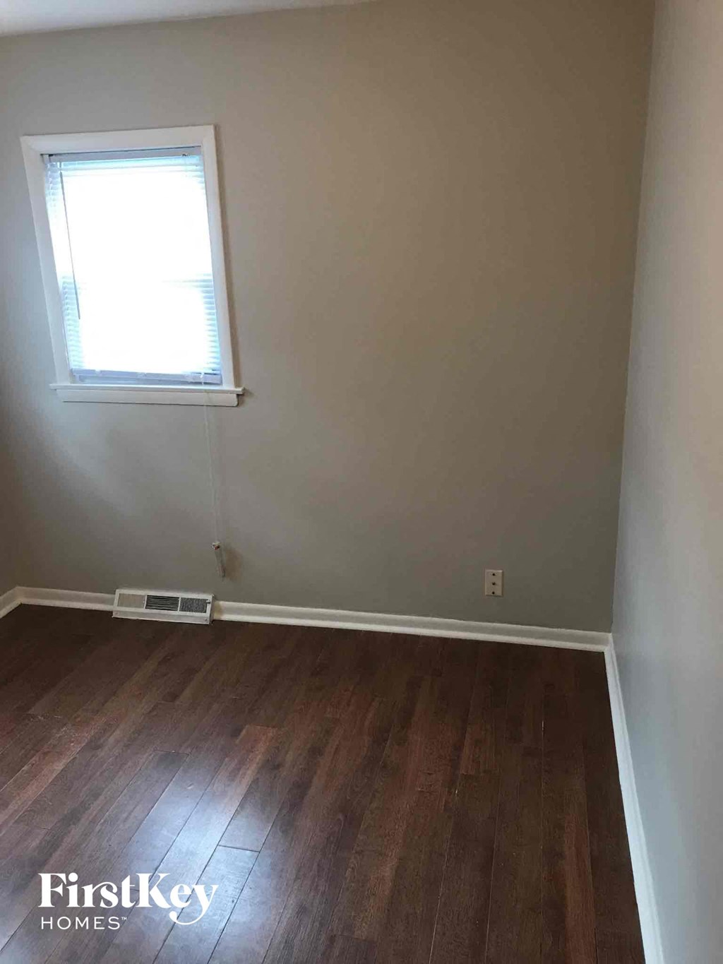 a empty room with a window and wooden floors
