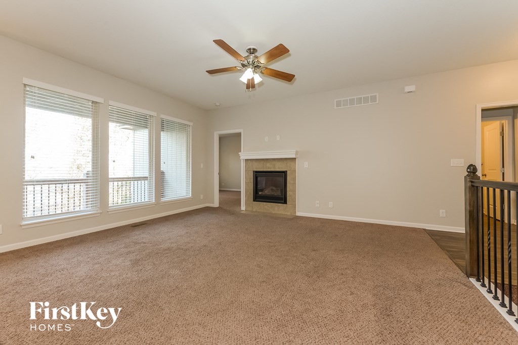 an empty living room with a ceiling fan and a fireplace