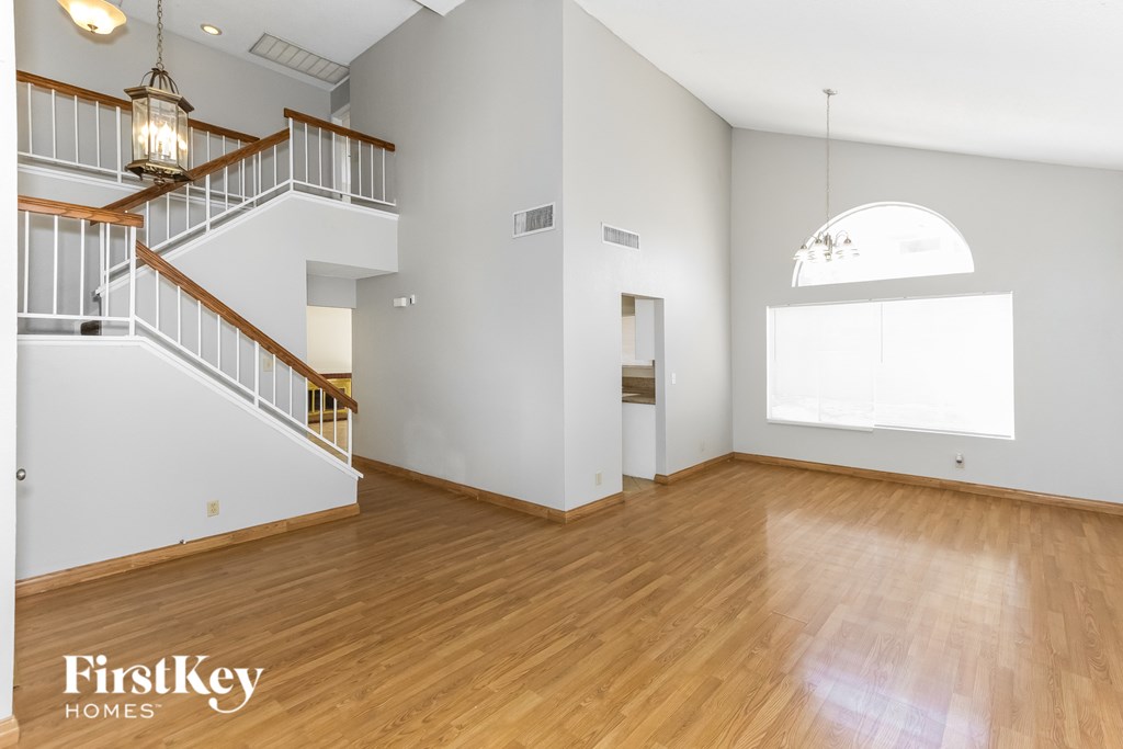 A spacious room with wooden floors and a staircase with a wooden handrail.