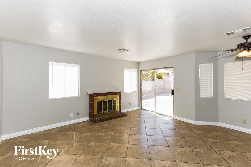 A spacious room with a fireplace and a ceiling fan.