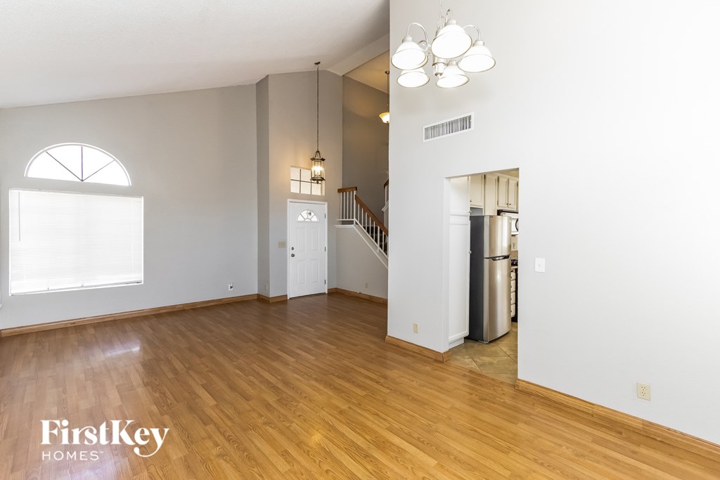 A spacious living room with wooden floors and a staircase leading to the upper level.