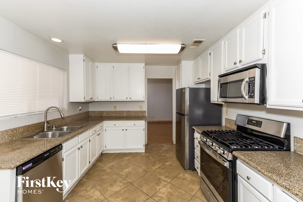 A kitchen with white cabinets and a black refrigerator.