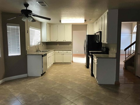 A kitchen with a fan and a refrigerator.