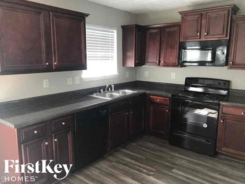 A kitchen with dark wood cabinets and black appliances.
