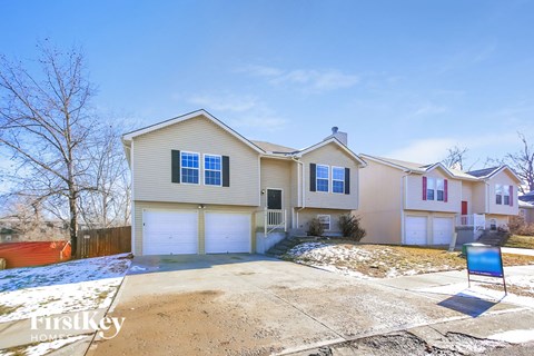 a beige house with white garage doors and snow on the ground