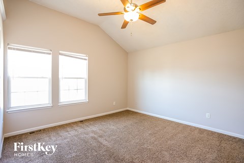 a bedroom with two windows and a ceiling fan