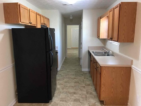 a kitchen with a black refrigerator and wooden cabinets