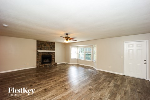 A spacious room with a fireplace and wood flooring.