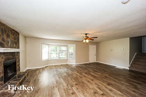 A room with a fireplace and wood flooring.