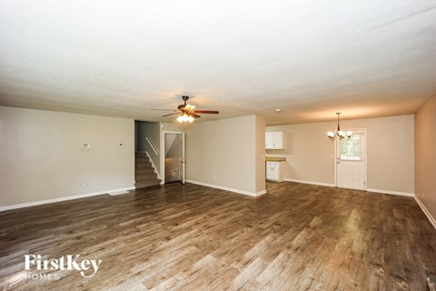 A spacious room with wooden flooring and a ceiling fan.