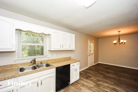 A kitchen with white cabinets and a wooden floor.