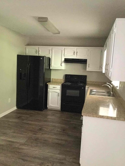 A kitchen with black appliances and white cabinets.