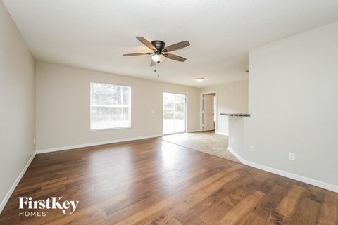 A spacious room with wooden floors and a ceiling fan.