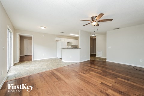 A spacious room with wooden floors and a ceiling fan.