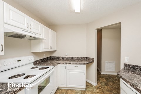 A kitchen with a white stove and marble countertops.