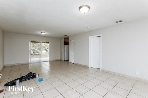 the living room is spacious and clean with white tile and a door to the backyard