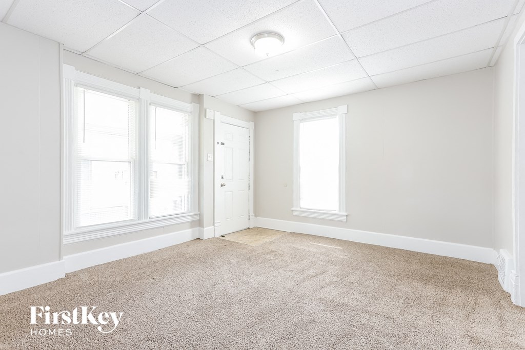 A carpeted room with a door and a window.