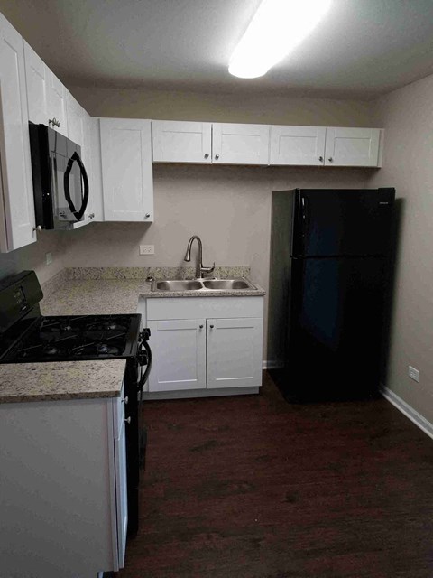 a kitchen with white cabinets and a black refrigerator