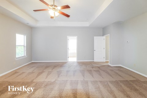A spacious room with a carpeted floor and a ceiling fan.