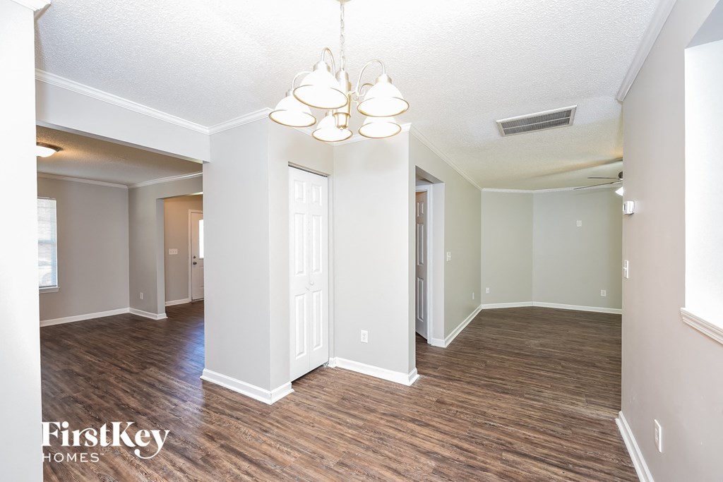 an empty living room and dining room with wood flooring and a chandelier