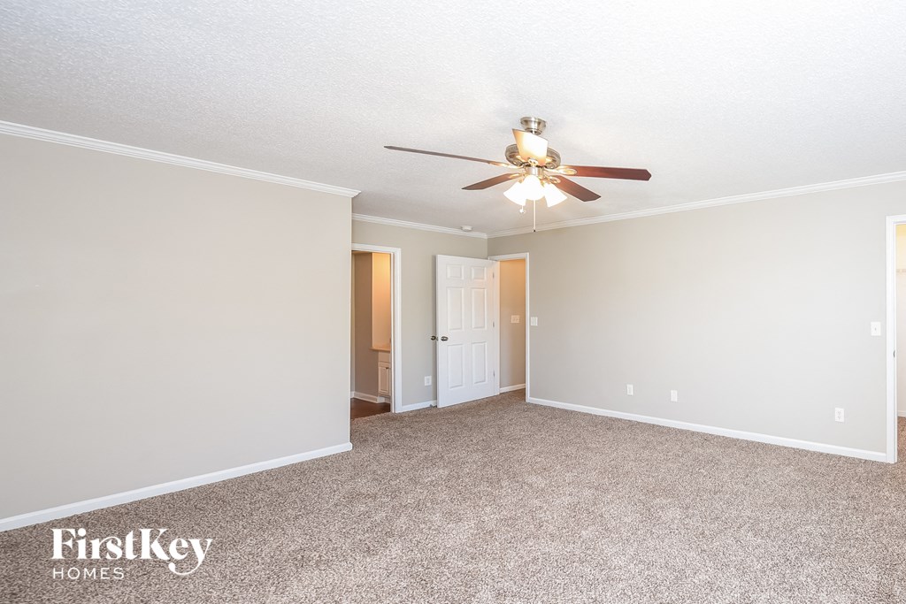 a empty living room with a ceiling fan and a door to a closet