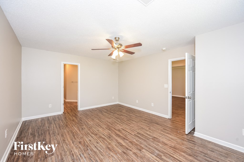 an empty living room with a ceiling fan and wood flooring