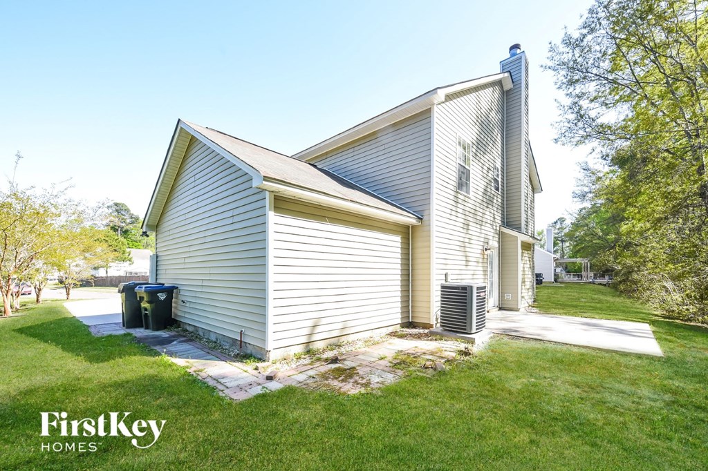 the side of a small house with a garage and a driveway