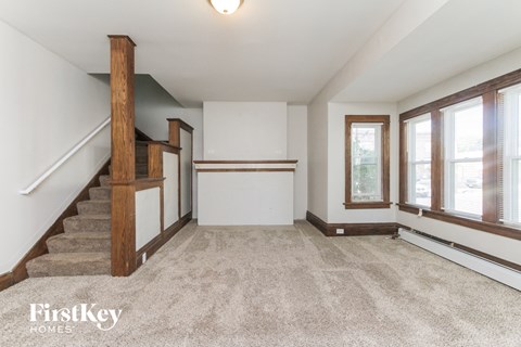 an empty living room with a staircase and windows