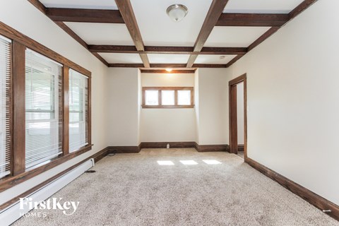 an empty living room with white walls and wood beams