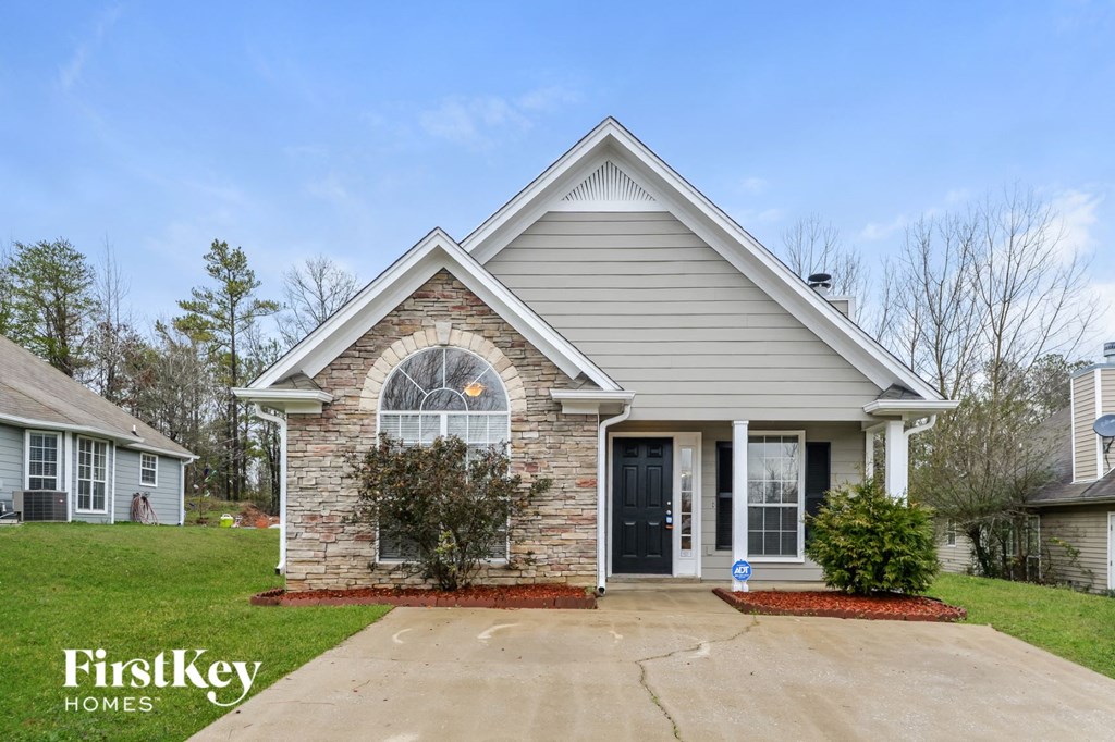 A house with a brick arched window and a black door is for sale.