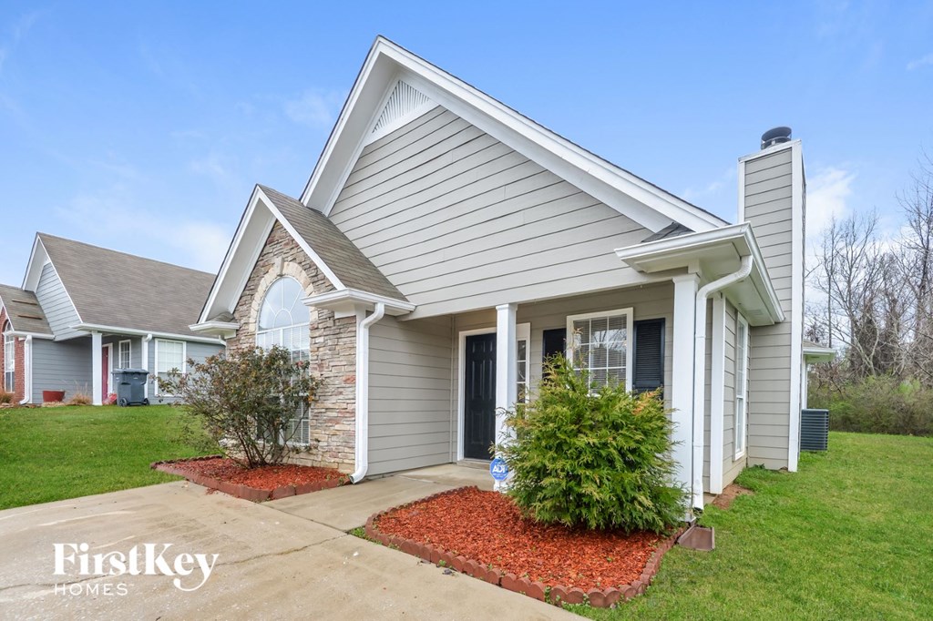 A house with a grey roof and a red brick chimney is for sale.