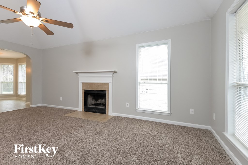 A spacious living room with a fireplace and a ceiling fan.