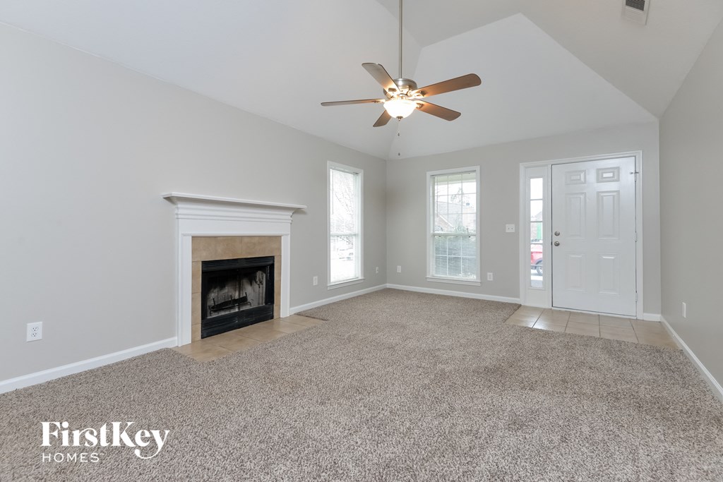 A spacious living room with a fireplace and a carpeted floor.