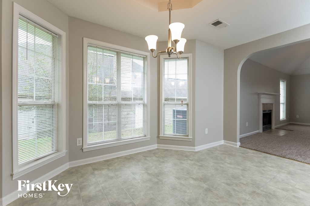 A spacious room with a chandelier and two windows.