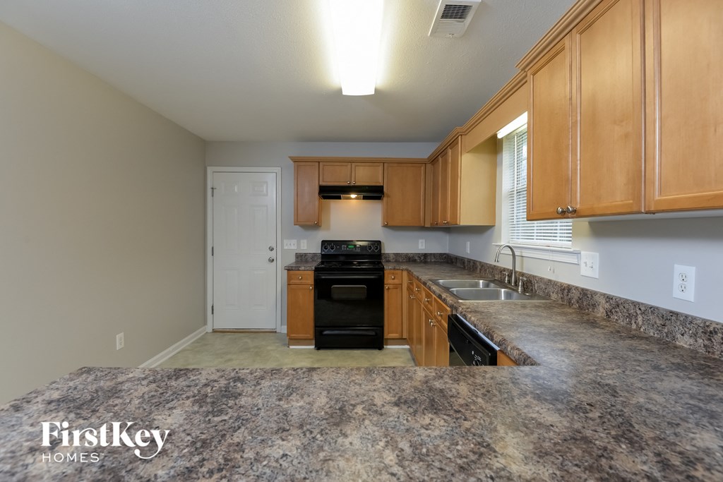 A kitchen with a black oven and wooden cabinets.