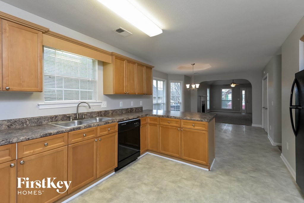 A kitchen with wooden cabinets and a black refrigerator.
