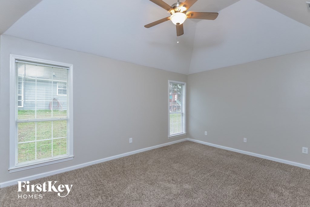 A room with a ceiling fan and a window overlooking a lawn.