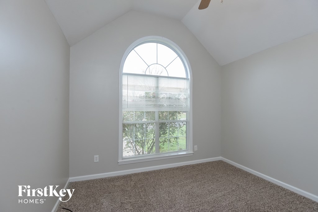 A room with a large arched window and a carpeted floor.