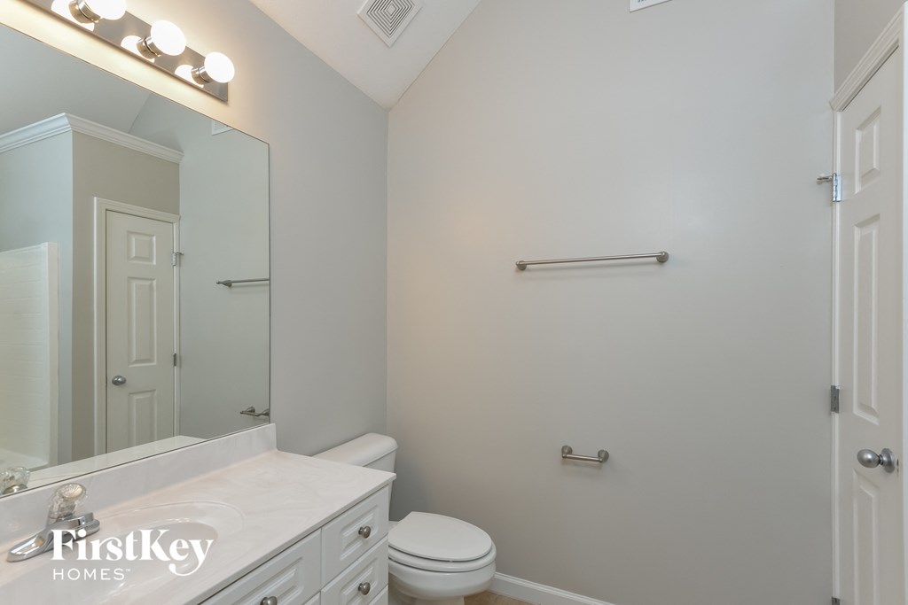 A white bathroom with a toilet, sink, and mirror.