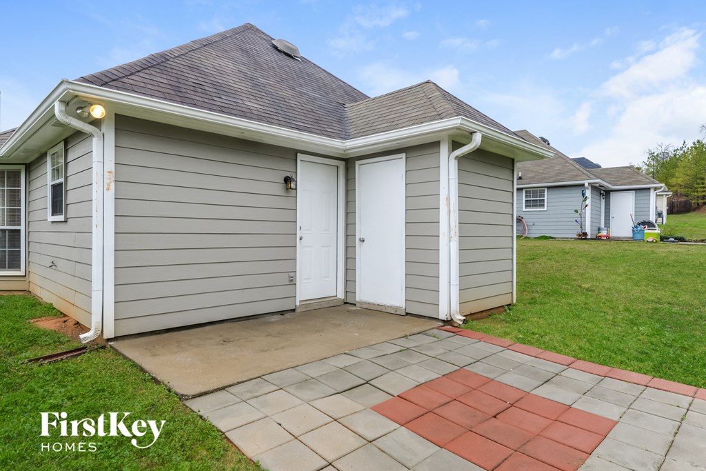 A small house with a grey siding and a white door is for sale.