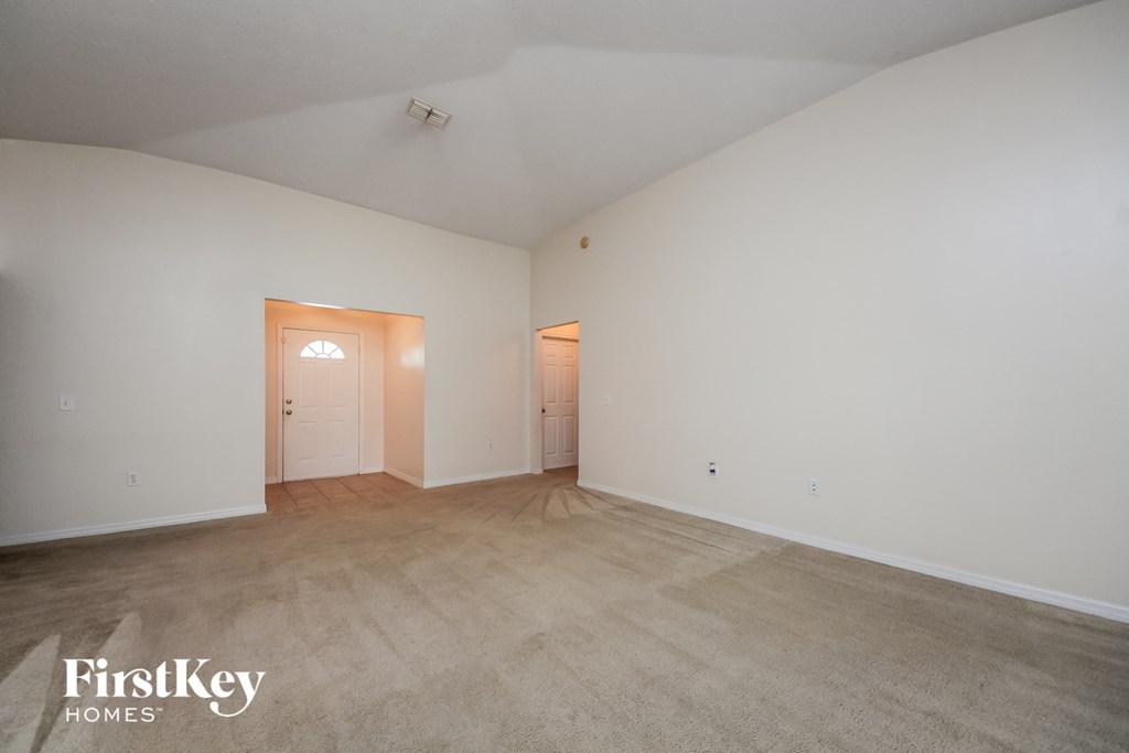 a spacious living room with carpet and white walls