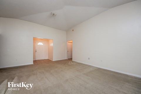 a spacious living room with carpet and white walls