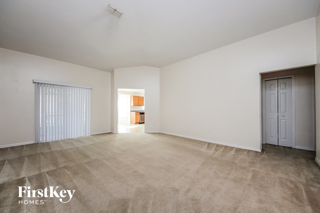 an empty living room with a door to a kitchen