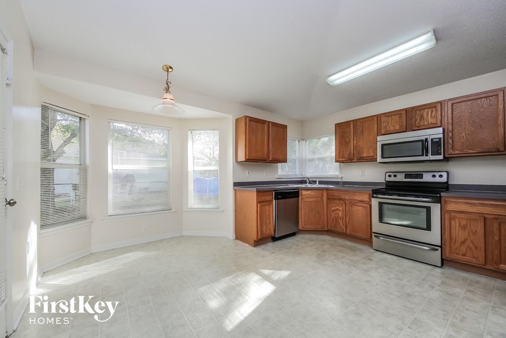 an empty kitchen with wooden cabinets and stainless steel appliances
