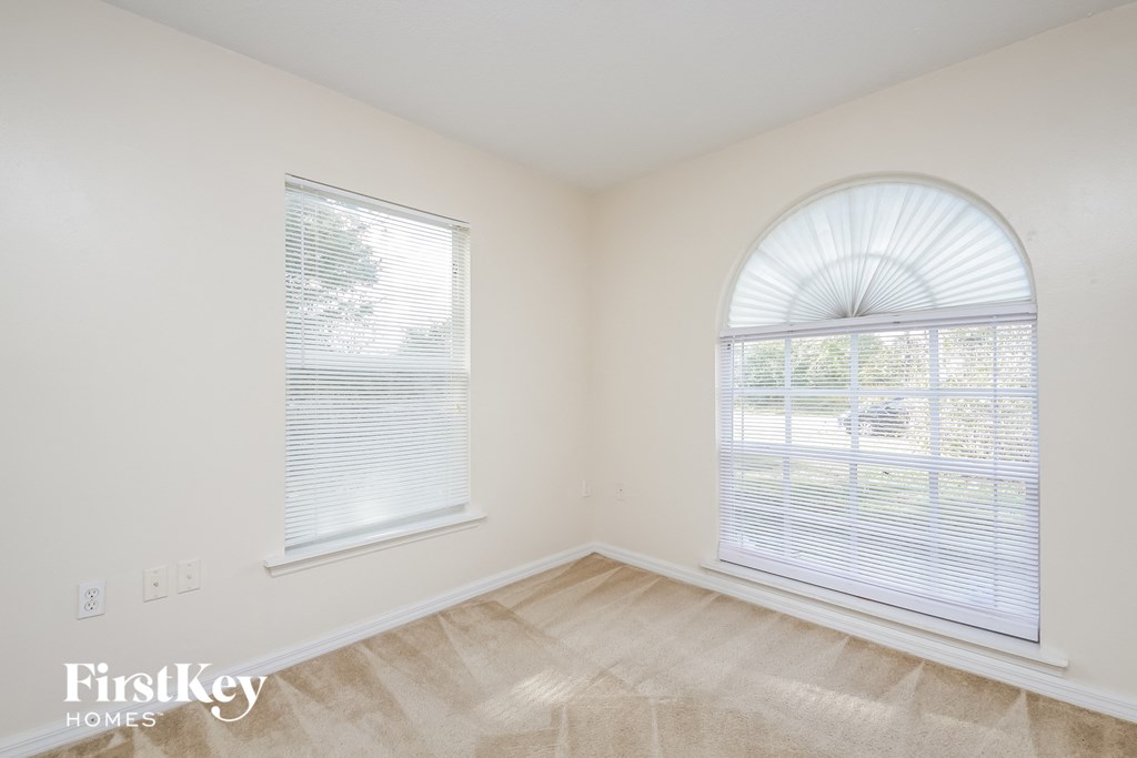 a bedroom with a large window and a carpeted floor