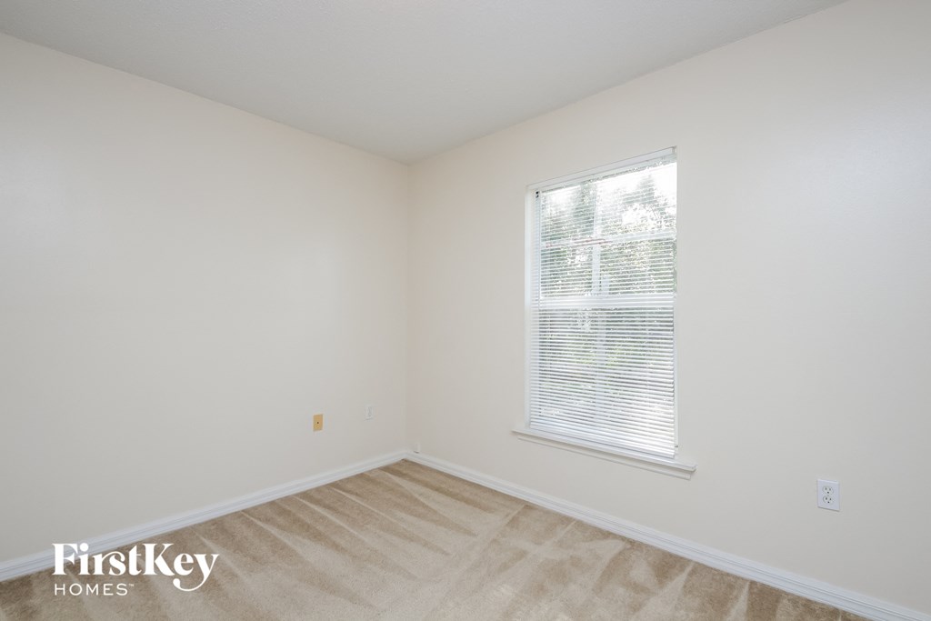 a bedroom with a large window and white walls and wood floors