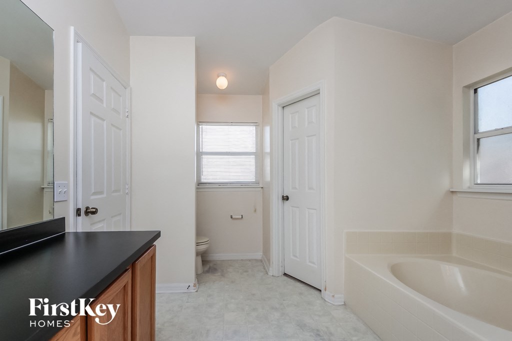 a white bathroom with a tub and a sink and a mirror